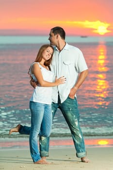 Young couple near the sea at sunrise