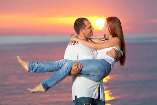 Young couple near the sea at sunrise