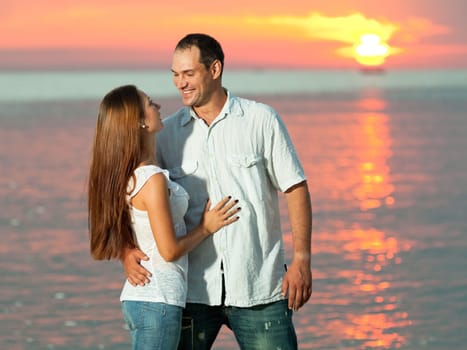 Young couple near the sea at sunrise