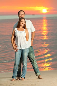 Young couple near the sea at sunrise