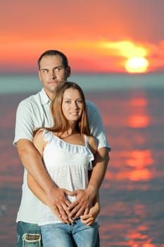 Young couple near the sea at sunrise