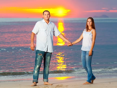 Young couple near the sea at sunrise