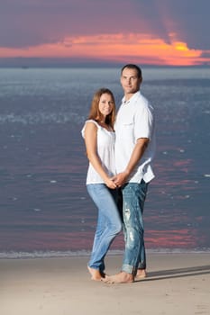 Young couple near the sea at sunrise