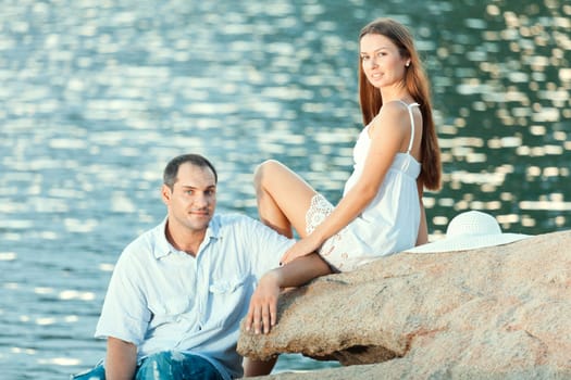Young couple sitting on the cliff near ocean