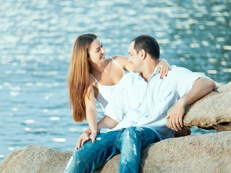 Young couple sitting on the cliff near ocean