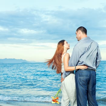 Young beautiful couple staying near the ocean