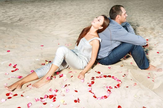 Couple on the tbeach. Yeart shape maked from petals