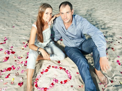 Couple on the tbeach. Yeart shape maked from petals