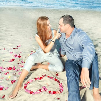 Couple on the tbeach. Yeart shape maked from petals