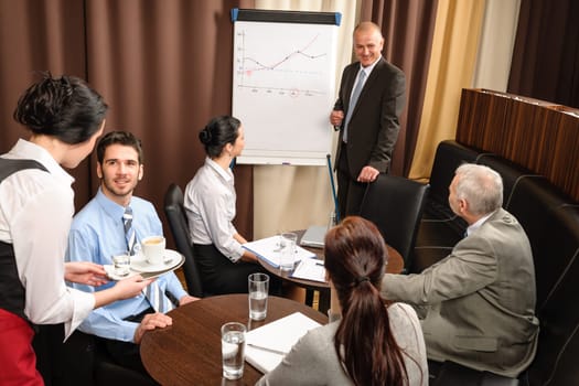 Executive businessman giving presentation on flip-chart to team formalwear