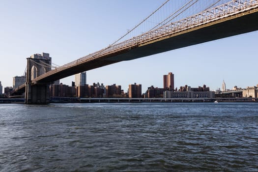 Empire State Tower visible under span of Brooklyn bridge in NY