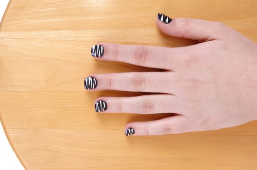 One hand from a teenage girl with polished fingernails sitting on a  wood chair.