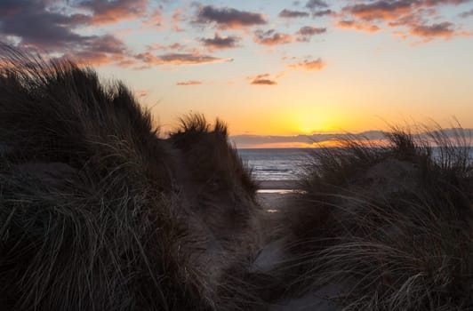 Sun setting over the beach at Formby in England through sand dunes
