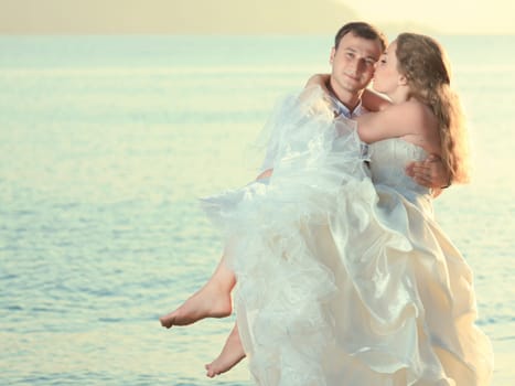 Groom holding up a his bride on the beach