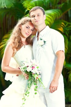 Portrait of bride and groom in a tropical garden.