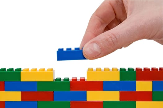 hand building up a wall by stacking up lego