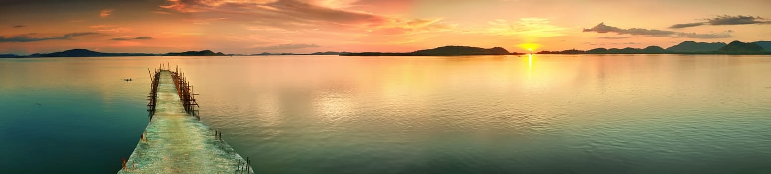 Sunset over the sea. Pier on the foreground. Panorama