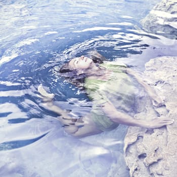 Woman like mermaid in wet dress in lake