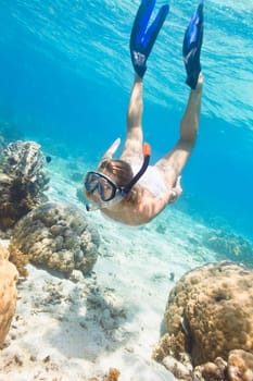 Beautiful woman diver swimming among the coral reef