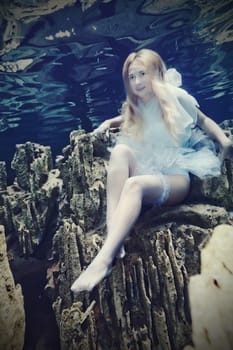 Young beautiful woman in white dress underwater