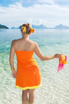 Woman in orange dress on the tropical beach
