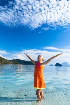 Woman in orange dress on the tropical beach