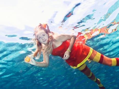 Underwater shot of a funny woman with orange