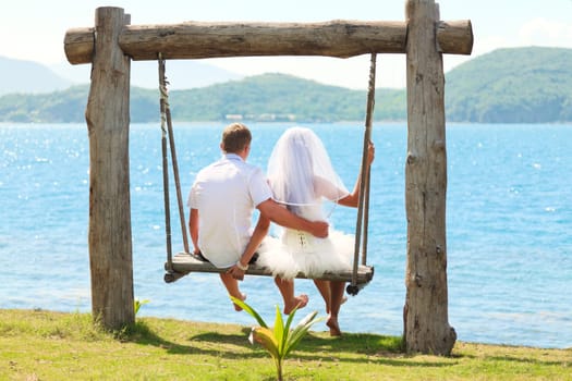 Rear view bride and groom on the swing
