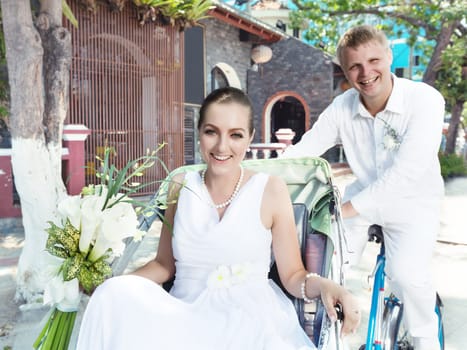 Groom and bride driving cyclo on the street