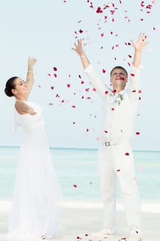Bbride and groom throwing petals on the  beach