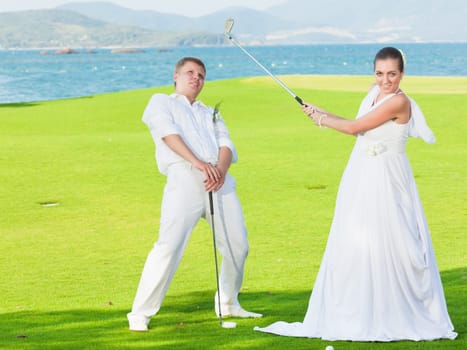 Bride and groom are playing golf at wedding day