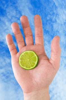 hand with lemon on the sky background