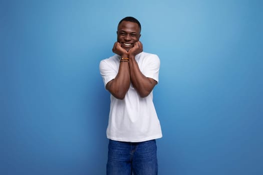 positive friendly young african man in white t-shirt on studio background with copy space.