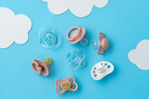 Many pacifiers on blue background with copy space, top view of soothers, flat lay