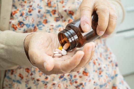 Asian senior woman patient holding antibiotics capsule pills  for treatment infection patient in hospital, Pharmacy drugstore concept.