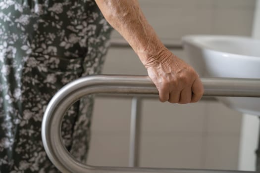 Asian elderly woman patient use toilet bathroom handle security in nursing hospital, healthy strong medical.