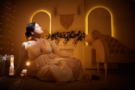 Owerweight elegant Woman at night or evening dark Christmas room. Fat plumb pretty girl in beautiful dress for a holiday. Popular buxom female model posing alone in New year sudio