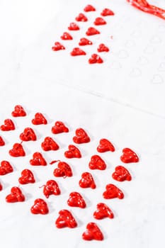 Piping melted chocolate from piping back over the parchment paper to make a chocolate heart.