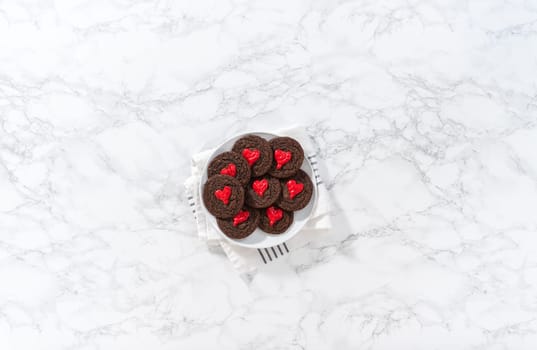 Flat lay. Decorating chocolate cookies with red chocolate hearts.