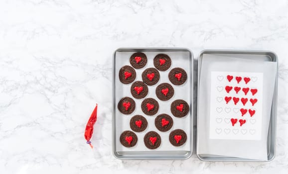 Flat lay. Decorating chocolate cookies with red chocolate hearts.