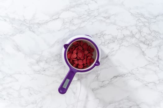 Flat lay. Melting red chocolate chips in a candy melting pot to make chocolate hearts for chocolate cookies.