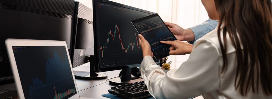 Group of traders discussing on office desk, monitoring stock market on monitor at office workplace. Businessman and broker analyzing stock graph together at stock trading company. Trailblazing