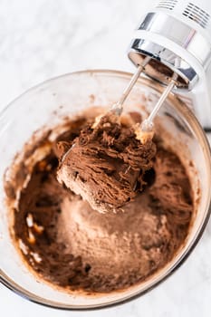 Mixing ingredients with a hand mixer to bake chocolate cookies with chocolate hearts for Valentine's Day.