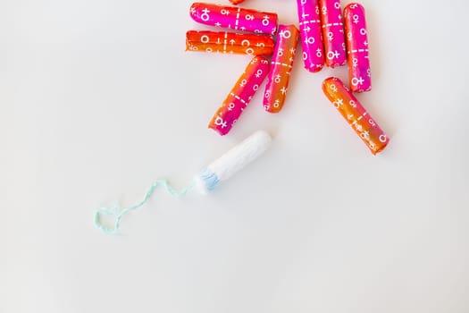 Medical female tampon in pink and orange packaging on a white background. Hygienic white tampon for women. Cotton swab. Menstruation, contraception