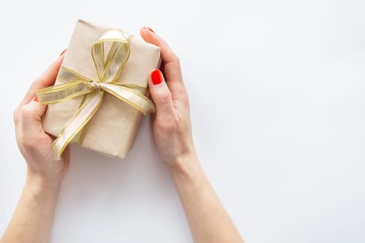 The girl holds a gift with a golden ribbon in her hands on a white background. Time to wrap presents. The concept of surprise, surprise loved ones
