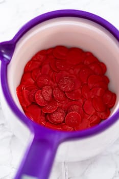 Melting red chocolate chips in a candy melting pot to make chocolate hearts for chocolate cookies.