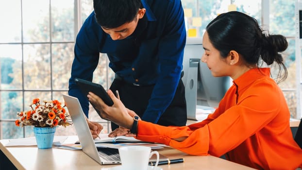 Two business people talk project strategy at office meeting room. Businessman discuss project planning with colleague at modern workplace while having conversation and advice on financial report. Jivy