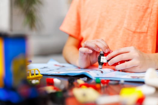 Child boy playing and building with colorful plastic bricks at the table. Early learning and development