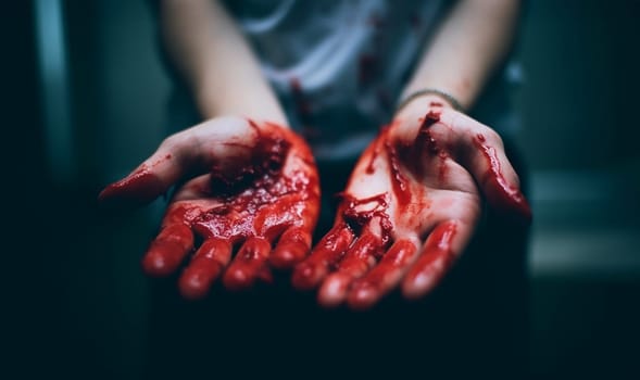 Hand of killed person or the killer with bloody hands. Abuse and domestic violence. horror or Halloween background or surface with bloody red hands prints on moody wall with copy space. Halloween background Space for text