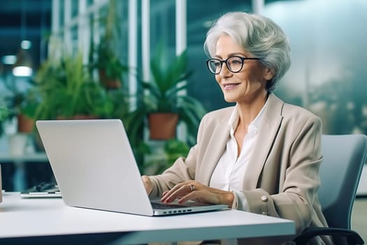 An old, successful woman works on a computer. High quality photo